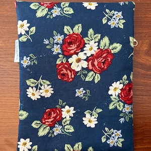 K&ouml;nnte beinhalten: Eine marineblaue Buchh&uuml;lle mit einem Blumenmuster aus roten Rosen, wei&szlig;en G&auml;nsebl&uuml;mchen und kleinen blauen Blumen mit gr&uuml;nen Bl&auml;ttern. Die H&uuml;lle hat ein kleines wei&szlig;es Etikett mit Text und einen Metallring.