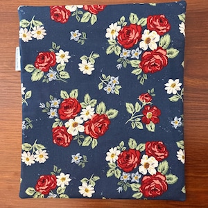 K&ouml;nnte beinhalten: Ein marineblaues Stoffst&uuml;ck mit einem Blumenmuster aus roten Rosen, wei&szlig;en G&auml;nsebl&uuml;mchen und kleinen blauen Blumen. Die Blumen sind in Clustern mit gr&uuml;nen Bl&auml;ttern angeordnet. Der Artikel ist rechteckig und scheint eine H&uuml;lle oder ein Bezug zu sein.