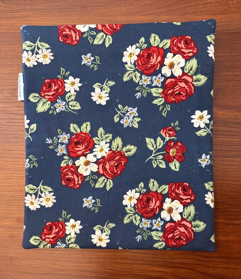 K&ouml;nnte beinhalten: Ein marineblaues Stoffst&uuml;ck mit einem Blumenmuster aus roten Rosen, wei&szlig;en G&auml;nsebl&uuml;mchen und kleinen blauen Blumen. Die Blumen sind in Clustern mit gr&uuml;nen Bl&auml;ttern angeordnet. Der Artikel ist rechteckig und scheint eine H&uuml;lle oder ein Bezug zu sein.