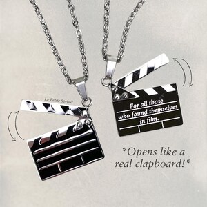 May include: Two silver necklaces with a silver clapperboard pendant. The clapperboard pendant opens like a real clapperboard. The text on the clapperboard reads "For all those who found themselves in film."