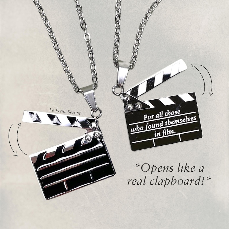 May include: Two silver necklaces with a silver clapperboard pendant. The clapperboard pendant opens like a real clapperboard. The text on the clapperboard reads "For all those who found themselves in film."