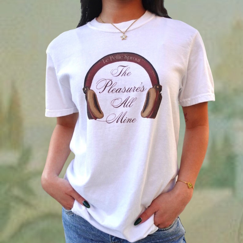 May include: White t-shirt with the text "Le Petite Sprout The Pleasure's All Mine" and a headphone graphic in burgundy and tan. The shirt is a crew neck style.