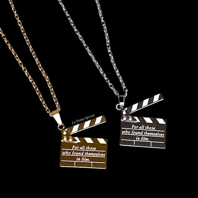 May include: Two gold and silver necklaces with a clapperboard pendant. The pendant has the text "For all those who found themselves in film."