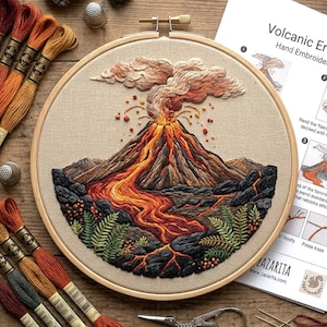 May include: A circular hand-stitched embroidery of a volcano erupting, set in a wooden hoop. The scene depicts a volcano with orange and red lava, dark rocks, and green plants. The embroidery is on beige fabric, with threads and tools visible.