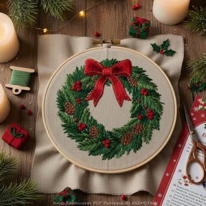 May include: Embroidered Christmas wreath in a wooden hoop. The wreath features green pine needles, red berries, and pine cones, with a large red bow at the top. The text "HAND EMBROIDERY PDF PATTERNS BY ZAZARITA" is at the bottom.