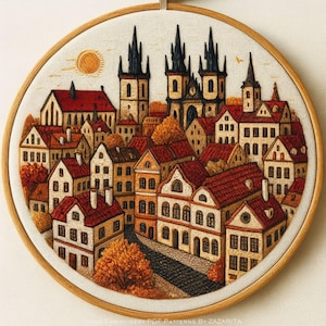 May include: Embroidered cityscape art in a wooden hoop. The artwork depicts a European town with red-roofed buildings, tall spires, and a cobblestone street. The color palette includes warm tones of orange, brown, and beige, with a sun in the sky.
