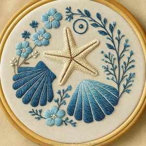 May include: Hand-embroidered hoop art featuring a starfish, seashells, and floral elements in shades of blue and cream. The design includes detailed stitching and is set against a neutral fabric background within a wooden hoop. The text "Hand Embroidery PDF Patterns By Zazarita" is at the bottom.