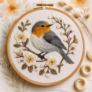 May include: Hand-stitched embroidery art featuring a bird with orange, gray, and white feathers perched on a branch with white flowers. The embroidery is set in a wooden hoop, showcasing a detailed, textured design. The artwork is a decorative piece.