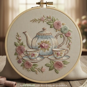 May include: Embroidered tea set design featuring a light blue teapot, two teacups, and saucers, surrounded by pink and green roses. The design is set within a wooden embroidery hoop. The text "HAND EMBROIDERY PATTERNS BY ZAZARITA" is at the bottom.