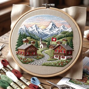May include: Embroidered Swiss landscape in a wooden hoop. The design shows a village with snow-covered mountains, a church, and houses with red shutters. A Swiss flag is visible. Embroidery threads and scissors are in the foreground.
