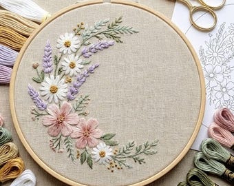 Puede incluir: Un bastidor de bordado floral con un diseño de media luna de flores rosas, blancas y lavanda con hojas verdes. El bordado está en un bastidor de madera, con madejas de hilo y tijeras doradas. El proyecto de manualidades está sobre tela de lino neutra.