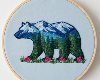 Könnte beinhalten: Gesticktes Kunstwerk einer Bärensilhouette, gefüllt mit einer Berg- und Waldszene. Der Bär ist blau, die Berge sind blau und weiß, und die Bäume sind grün. Am unteren Rand befinden sich rosa Blumen und grünes Gras. Der Text "Hand Embroidery Patterns By Zazarita" befindet sich unten.