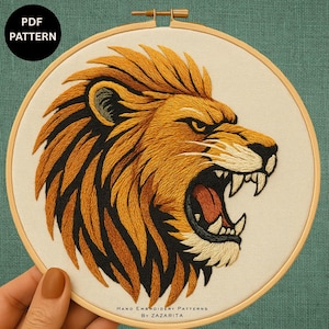 May include: Embroidered lion head in a wooden hoop. The lion's mane is a mix of orange and black threads, with a detailed face and open mouth. The text "PDF PATTERN" is in a black circle.