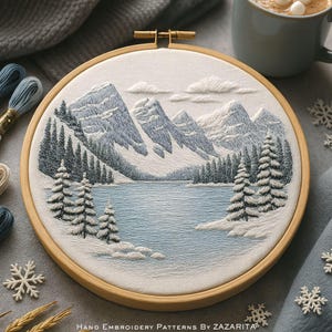 Puede incluir: Un bastidor de bordado redondo de madera con un paisaje invernal bordado. El diseño incluye montañas nevadas, un lago y árboles de hoja perenne, en tonos azules, blancos y grises. El texto "Hand Embroidery Patterns By Zazarita" está en la parte inferior.