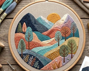 Könnte beinhalten: Ein runder Stickrahmen mit einer auf beigem Stoff gestickten Landschaft. Das Motiv zeigt dunkelblaue Berge, eine gelbe Sonne und sanfte Hügel in Blaugrün, Pfirsich und Beige. Verschiedene Bäume und kleine Pflanzen sind eingestickt.
