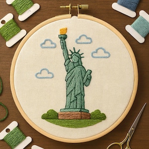 Peut inclure: Broderie sur tambour représentant la Statue de la Liberté. La statue verte tient une torche jaune. Des nuages bleus et de l'herbe verte sont également brodés. Le tout est encadré dans un cercle en bois.