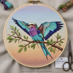 May include: Embroidered artwork of a vibrant bird with open wings, showcasing blue, purple, and brown hues, perched on a branch with green leaves. The embroidery is set in a wooden hoop. The text reads: Hand Embroidery PDF Patterns By Zazarita.