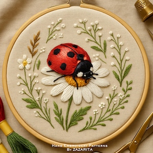 May include: Hand-embroidered artwork in a wooden hoop features a red ladybug with black spots atop a white daisy. Green leaves and small white flowers surround the daisy. The text "HAND EMBROIDERY PATTERNS BY ZAZARITA" is at the bottom.