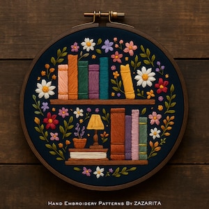 Op de afbeelding: Handgeborduurde hoepelkunst met een boekenplankontwerp. Het kunstwerk toont kleurrijke boeken, bloemen en een kleine lamp, alles tegen een donkerblauwe achtergrond. De houten hoepel heeft een diameter van ongeveer 20 cm.