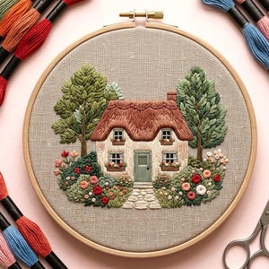 May include: Embroidered cottage scene in a wooden hoop. The cottage features a thatched roof, green door, and is surrounded by trees and flowers. Embroidery threads in various colours are visible around the hoop.