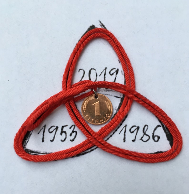 May include: A red cord knot with a copper coin pendant. The coin has the number 1 and the word "Pfennig" on it. The knot is drawn over the numbers 1953, 1986, and 2019.