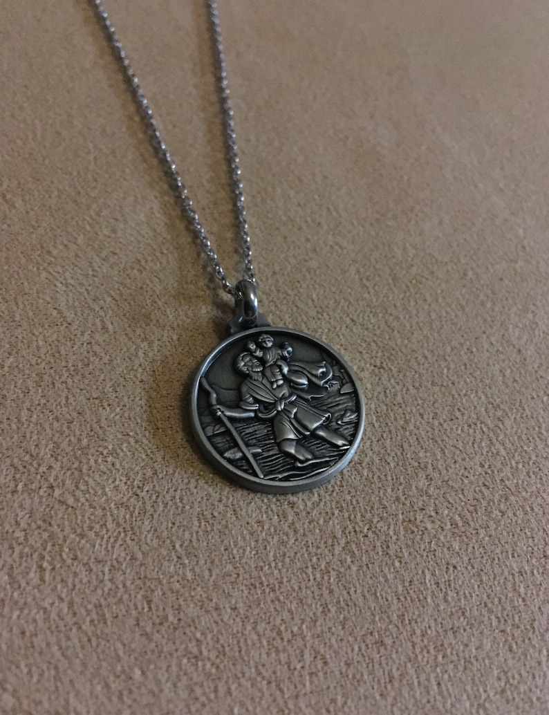 Może przedstawiać: Srebrny naszyjnik z okrągłym wisiorkiem przedstawiającym szczeg&oacute;łowy obraz mężczyzny niosącego dziecko na ramionach.