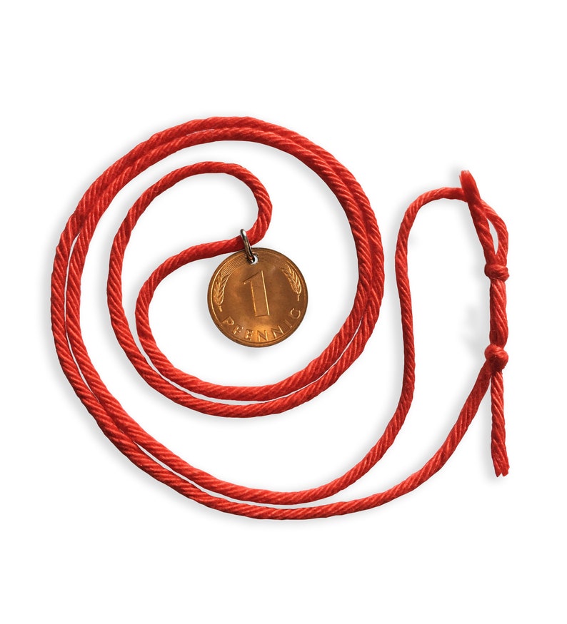 May include: A red cord necklace with a bronze coin pendant. The coin features the number "1" and the word "Pfennig". The cord is knotted at the end.