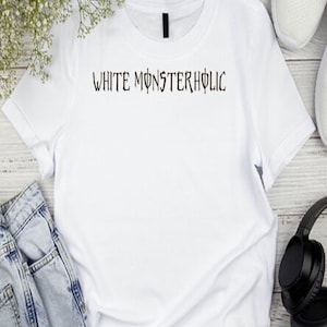 May include: White t-shirt featuring the text "WHITE MONSTERHOLIC" in a gothic font. The shirt is shown with blue jeans, white trainers, and black headphones. The shirt is made of a soft, white material.