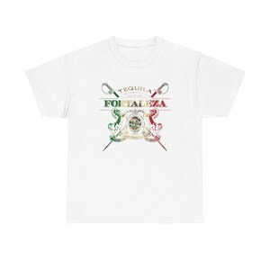 May include: White t-shirt with a graphic design featuring crossed swords and the text "Tequila Fortaleza" in a gold font. The swords are decorated with the colors of the Mexican flag.