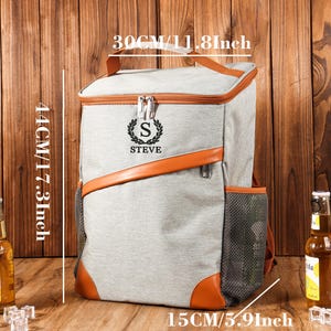 Pu&ograve; includere: Zaino termico grigio con dettagli in pelle marrone, misura 44 cm di altezza, 30 cm di larghezza e 15 cm di profondit&agrave;. Presenta una tasca laterale in rete e il nome "STEVE" con l'iniziale "S".