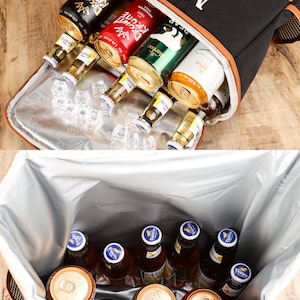 Pu&ograve; includere: Borsa termica isolante nera e arancione con le iniziali "MH" ricamate in bianco. La borsa contiene varie bottiglie e lattine di birra, alcune su cubetti di ghiaccio. La borsa frigo &egrave; aperta, rivelando il contenuto.