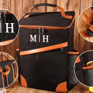 Pu&ograve; includere: Zaino termico nero con dettagli marroni e le iniziali "M|H" in bianco. Presenta una maniglia superiore, una tracolla e tasche laterali in rete. Include chiusura con cerniera e finiture marroni.