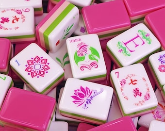 May include: A selection of Mahjong tiles in various colours. The tiles display diverse designs, including floral patterns, numbers, and Chinese characters. The tiles are white with pink, green, and other colour accents. Some tiles have the word "Joker" printed on them.