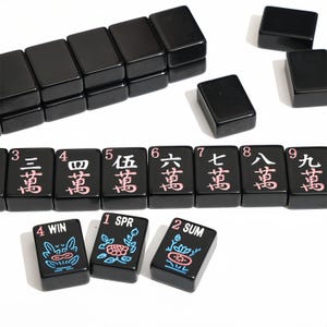 May include: A collection of black Mahjong tiles with white and pink characters. Some tiles are stacked, while others are scattered. The tiles feature numbers and symbols, including "WIN", "SPR", and "SUM".