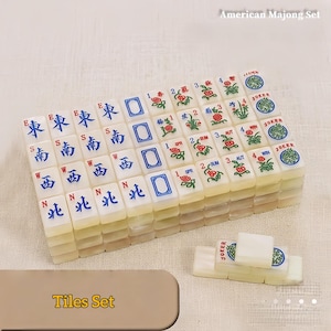 May include: An American Majong set featuring off-white rectangular tiles with blue and red ink designs. The tiles display directional characters, floral motifs, seasonal labels, and Joker tiles. The text American Majong Set is visible.