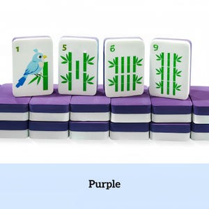 May include: A set of purple and white Mahjong tiles with green bamboo and bird illustrations. The tiles are stacked on a purple base. The numbers 1, 5, 6, and 9 are visible on the tiles. The word "Purple" is at the bottom.