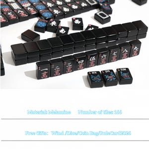 May include: A complete set of black Mahjong tiles, featuring Chinese characters and symbols in red and white. The set includes 166 tiles made of melamine. Some tiles have floral and number designs.