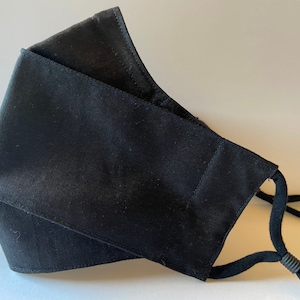 May include: Black face mask with adjustable ear loops. The mask is made of a soft, breathable fabric.