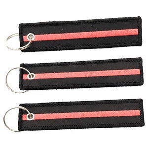 May include: Three black keychains with a single red stripe. Each keychain has a silver metal ring.