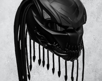 Può includere: Un casco da moto nero con un design da predatore e una lunga treccia nera. Il casco ha una visiera e una superficie testurizzata.