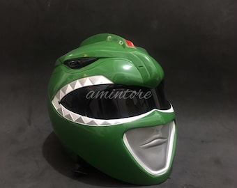 May include: Green Power Ranger helmet with a white and gray face mask and a white and gray tooth design. The helmet has a black visor.