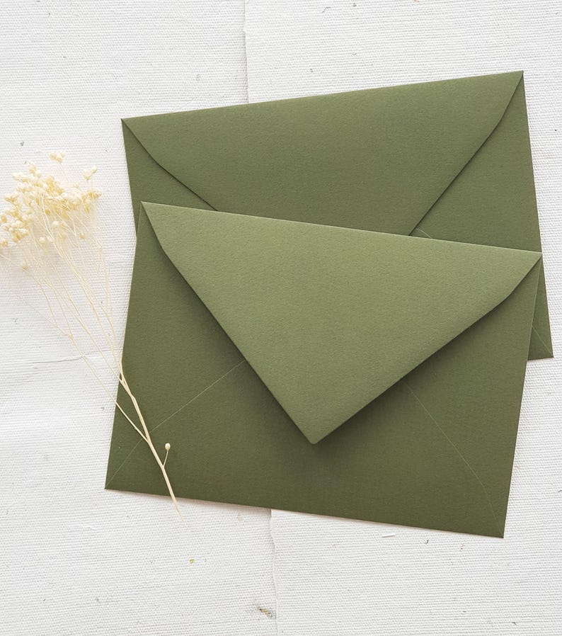 May include: Two green envelopes stacked on top of each other. The envelopes are made of a textured paper and have a pointed flap.