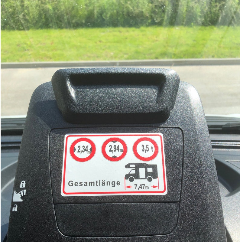 May include: A black dashboard display with a white sticker showing the dimensions of a vehicle. The sticker reads "Gesamtl&auml;nge 7,47m" and includes three red circles with the text "2,34m", "2,94m", and "3,5 t".