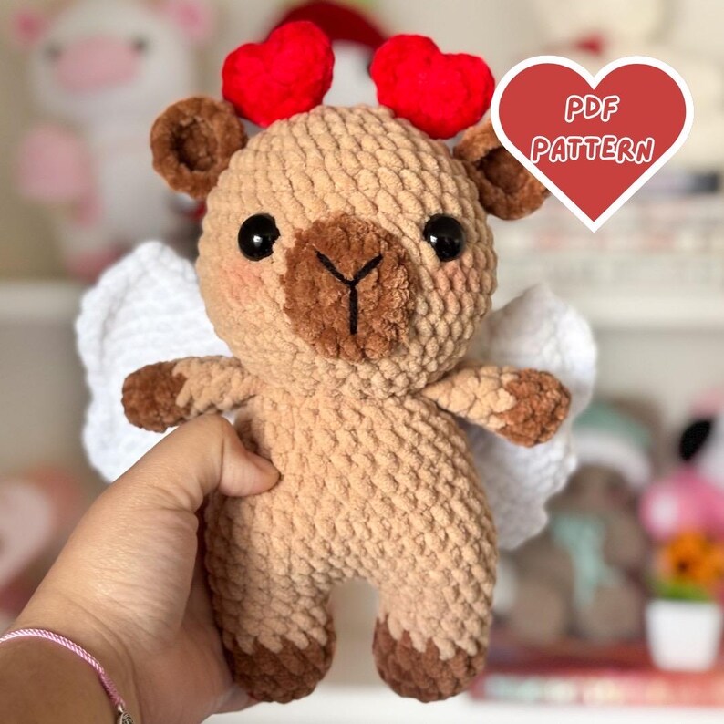 Puede incluir: Patr&oacute;n de amigurumi de crochet para una oveja marr&oacute;n y beige con alas blancas y cuernos de coraz&oacute;n rojo. El patr&oacute;n est&aacute; disponible para descargar en PDF. PDF PATTERN