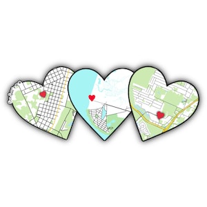 May include: Three heart-shaped map cutouts with red heart markers. The maps feature green and white areas with black street grids. The hearts are arranged side by side against a white background, suggesting a personalized gift or decor item.
