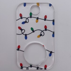 May include: A white acrylic keychain with a string of colorful Christmas lights printed on it. The keychain has a round hole in the center for attaching to a key ring.