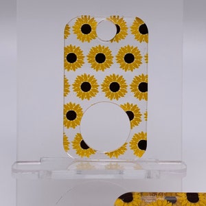 May include: A clear acrylic keychain with a sunflower pattern. The keychain has a round hole in the center for attaching keys.