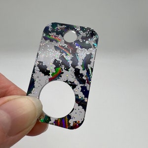 May include: A clear acrylic keychain with a glittery black and white bat pattern. The keychain has a round hole for attaching keys.