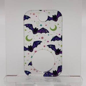May include: A clear acrylic keychain with a purple and black bat pattern on a white background. The bats are flying against a backdrop of stars and crescent moons.