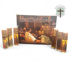May include: A set of four small glass bottles containing 100% pure nard oil. The bottles are labeled with the words "100% Pure Nard" and have a gold and white label. The bottles are arranged in a row on a white surface. The bottles are in front of a box with a painting of a biblical scene. The box has the words "Holy Land Bible Gifts" on it. The text on the box reads: "Then Mary took a pound of very costly oil of spikenard, anointed the feet of Jesus, and wiped his feet with her hair. And the house was filled with the fragrance of the oil (John 12.3)"